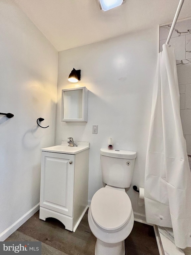 bathroom with curtained shower, toilet, wood finished floors, vanity, and baseboards