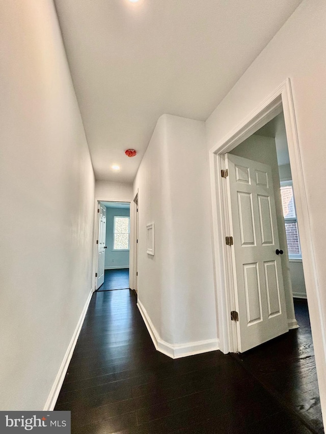 corridor featuring dark wood finished floors and baseboards