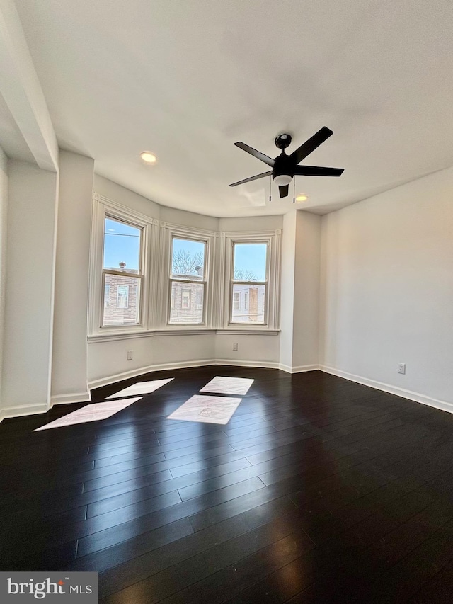 unfurnished room featuring ceiling fan, dark wood finished floors, and baseboards