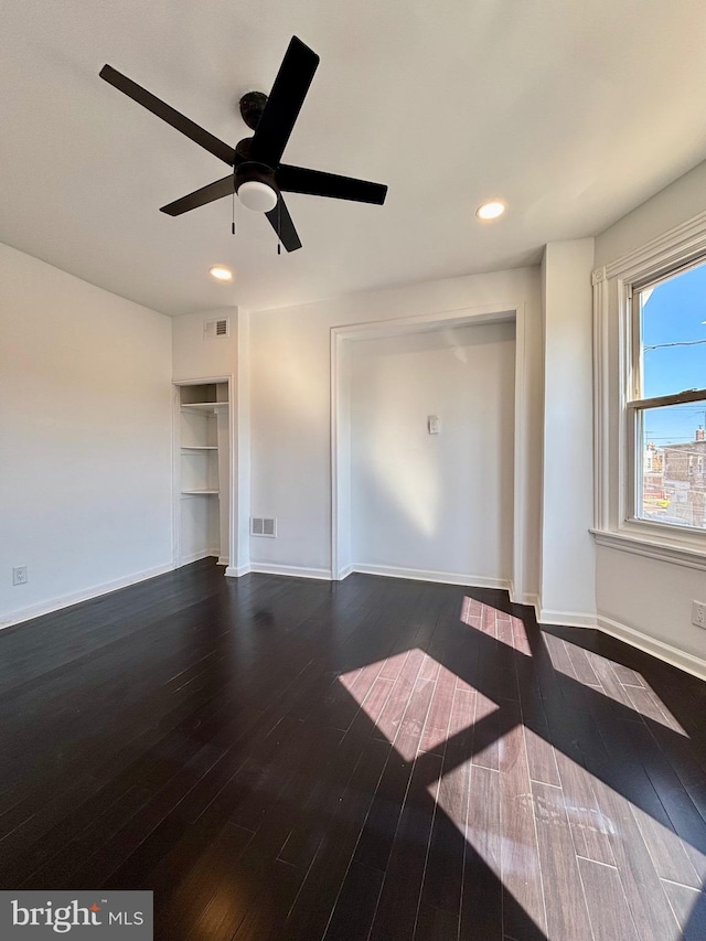 unfurnished living room featuring baseboards, visible vents, and dark wood-style flooring