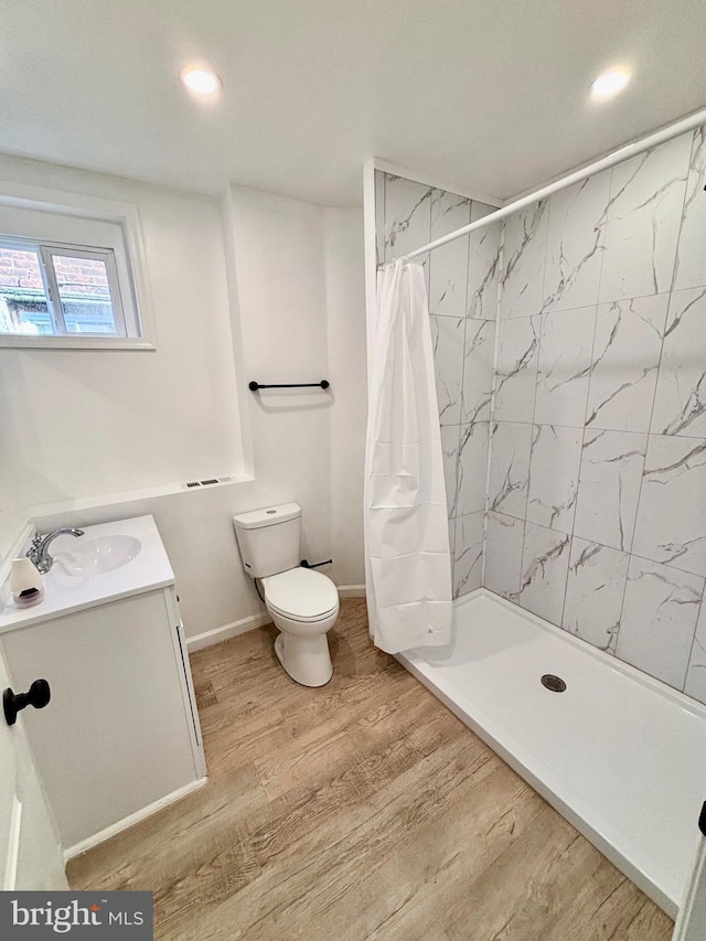 full bath with toilet, a shower stall, wood finished floors, and vanity