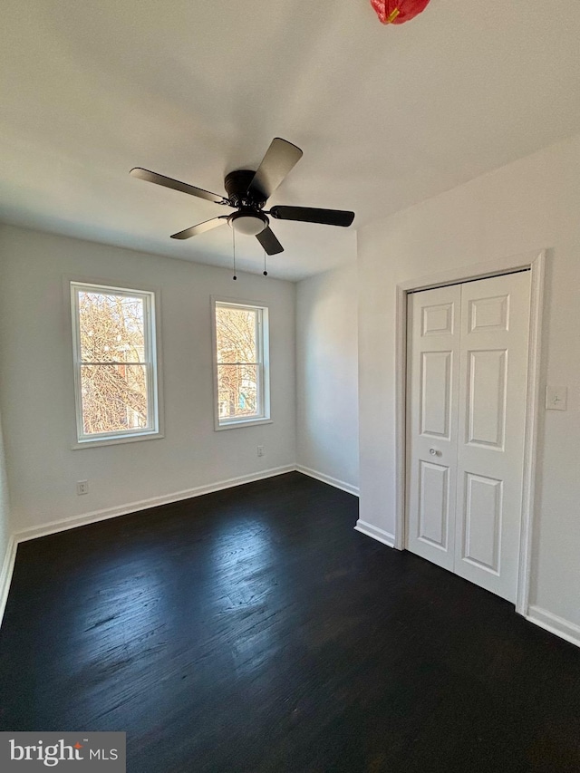 unfurnished bedroom featuring a ceiling fan, baseboards, and dark wood-type flooring