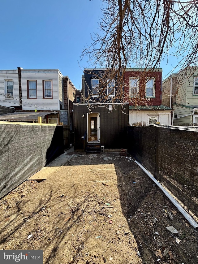 rear view of property with entry steps and fence