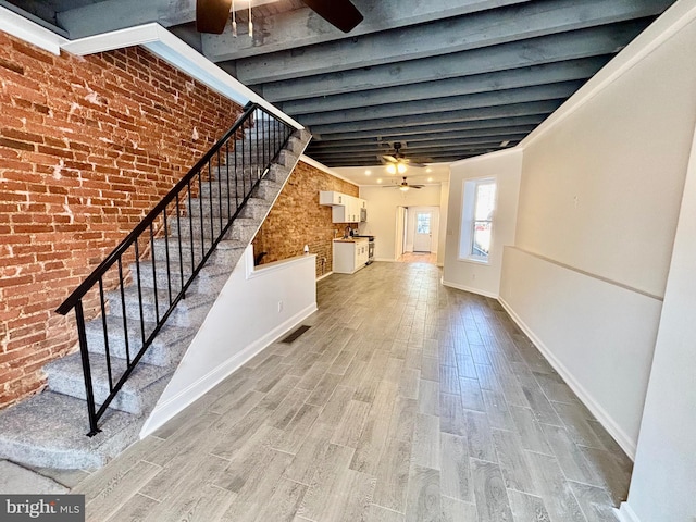 interior space featuring visible vents, brick wall, wood finished floors, and a ceiling fan