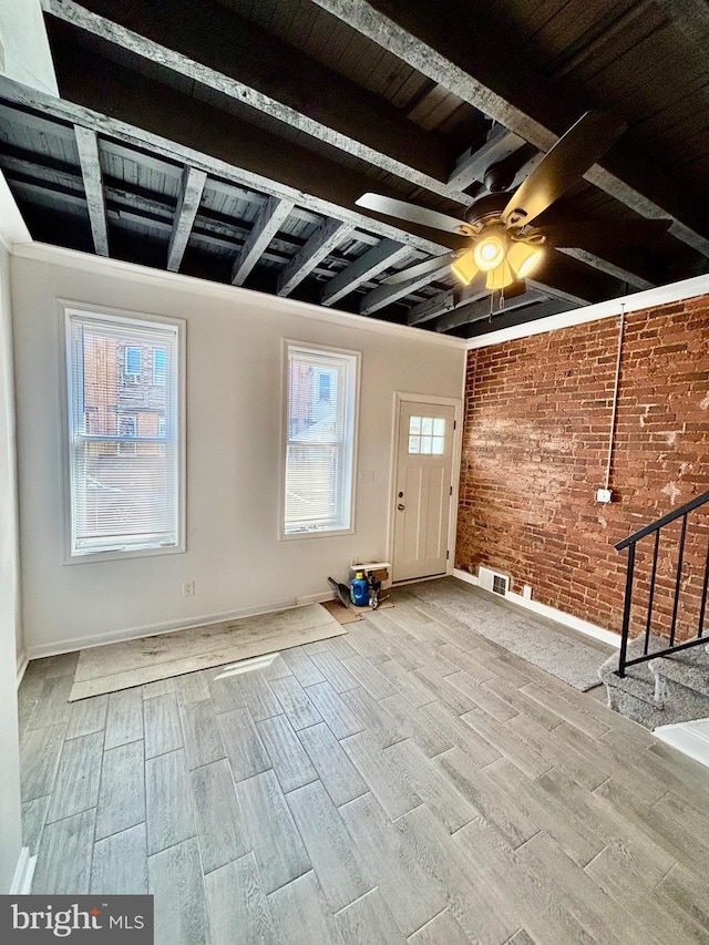 interior space featuring brick wall, stairway, plenty of natural light, and wood finished floors