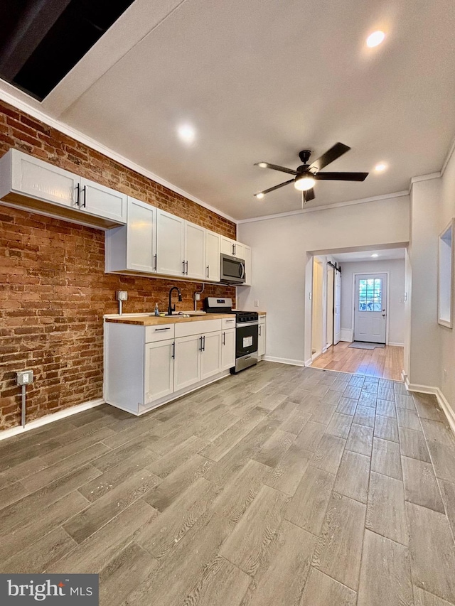 kitchen featuring appliances with stainless steel finishes, light wood-type flooring, and brick wall