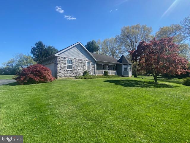 ranch-style home with a front lawn, an attached garage, and stone siding