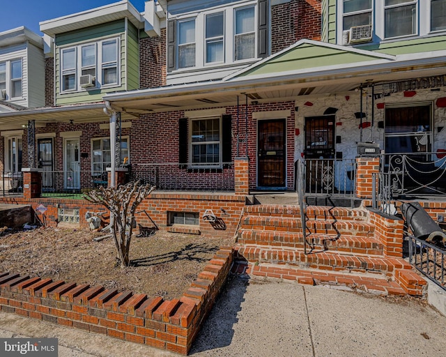 view of front facade featuring covered porch, brick siding, and cooling unit