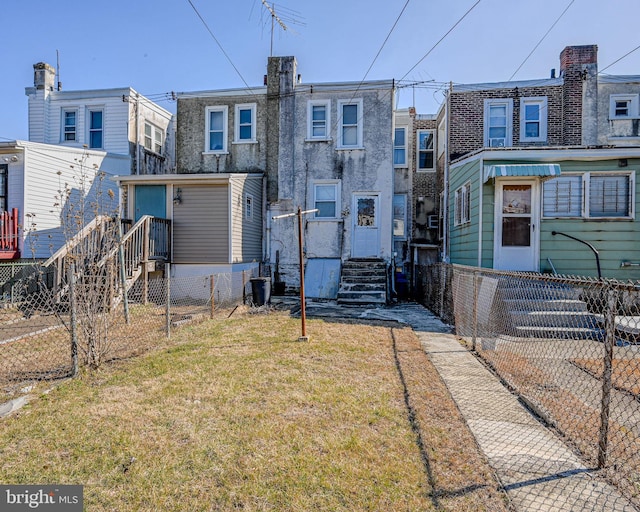 back of house featuring entry steps, fence, and a lawn