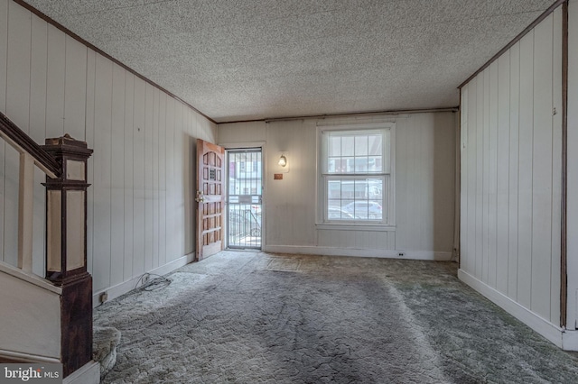 interior space with carpet flooring, crown molding, a textured ceiling, and stairs