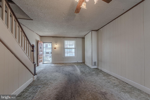 interior space with carpet floors, stairway, a ceiling fan, a textured ceiling, and baseboards