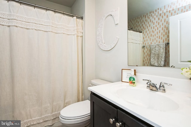 full bathroom with vanity, toilet, and wallpapered walls