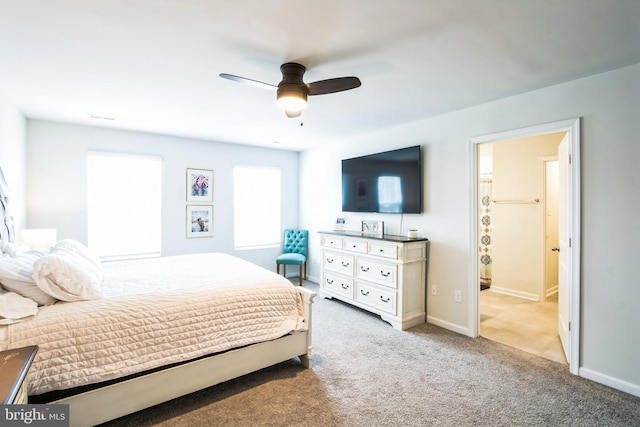 carpeted bedroom featuring ensuite bath, a ceiling fan, and baseboards