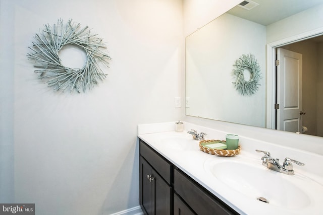 bathroom featuring double vanity, a sink, visible vents, and baseboards