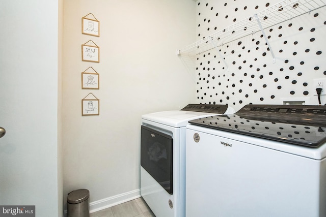 laundry room with laundry area, washing machine and dryer, baseboards, and light tile patterned flooring