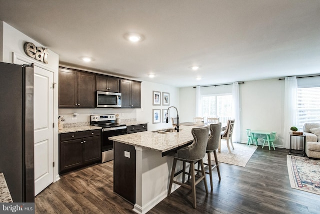 kitchen featuring dark wood-style floors, stainless steel appliances, a wealth of natural light, a sink, and dark brown cabinetry