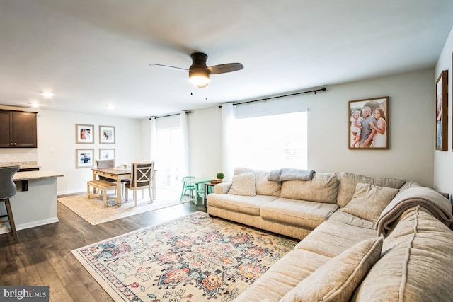 living area with dark wood-style flooring, plenty of natural light, baseboards, and ceiling fan