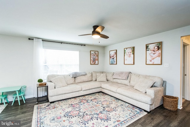 living room with dark wood-style floors, a ceiling fan, and baseboards