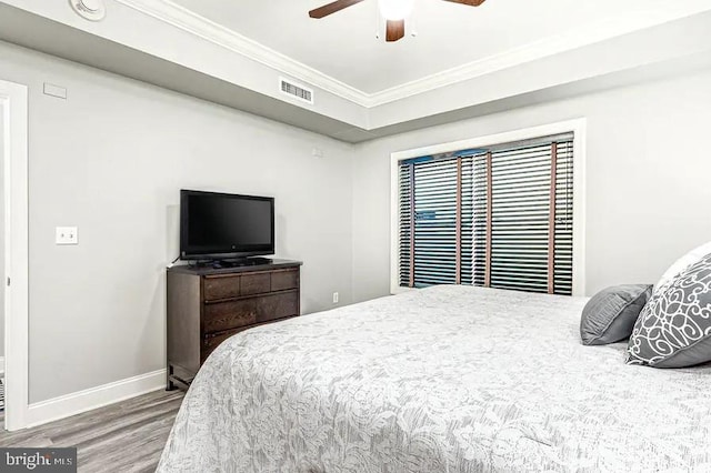 bedroom with crown molding, visible vents, a ceiling fan, wood finished floors, and baseboards