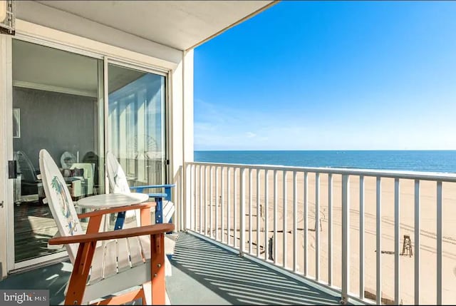 balcony with a water view and a view of the beach