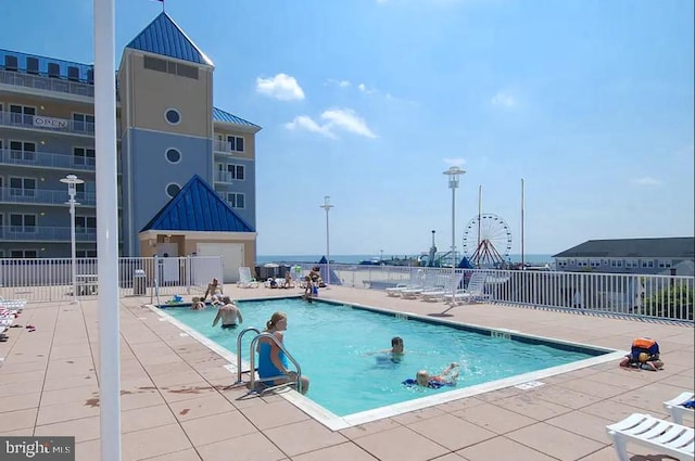 community pool with a patio and fence