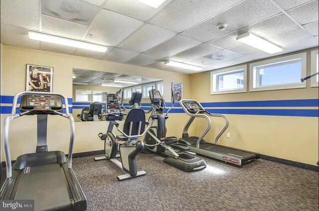 workout area with a paneled ceiling and baseboards