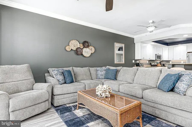 living area featuring a ceiling fan, light wood-style floors, and crown molding