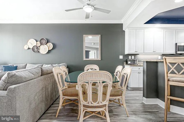 dining room with ceiling fan, a toaster, wood finished floors, and crown molding