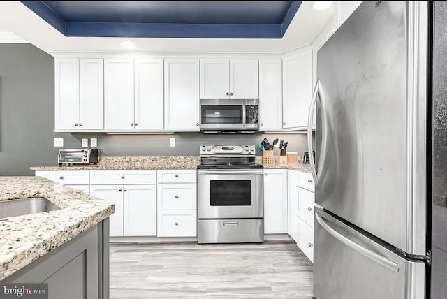 kitchen featuring appliances with stainless steel finishes, light stone countertops, and white cabinets