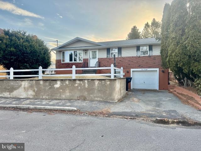 view of front of house with a garage, a fenced front yard, aphalt driveway, and brick siding