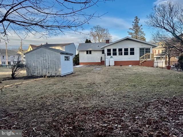 back of house featuring an outbuilding, fence, a yard, a shed, and a chimney