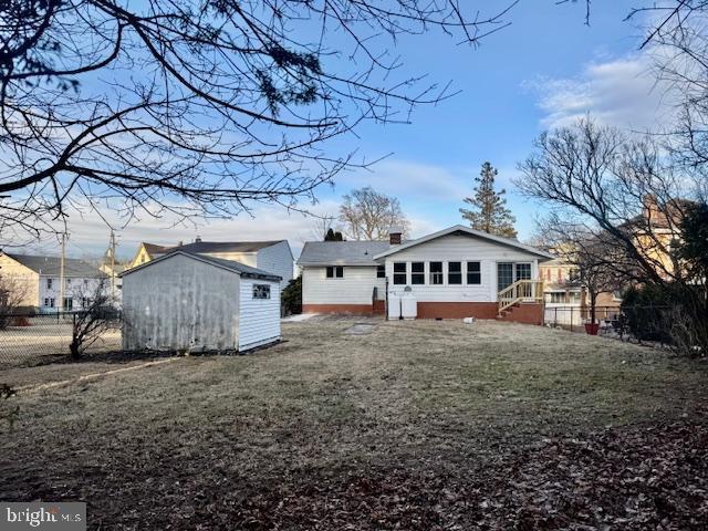 rear view of property with an outdoor structure, fence, a yard, a shed, and a chimney