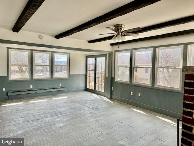 empty room with ceiling fan, a baseboard heating unit, wood finished floors, wainscoting, and beam ceiling