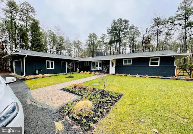 single story home featuring a front yard, an attached garage, a chimney, aphalt driveway, and board and batten siding