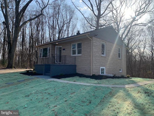 view of front of home with stone siding, a chimney, and a front yard