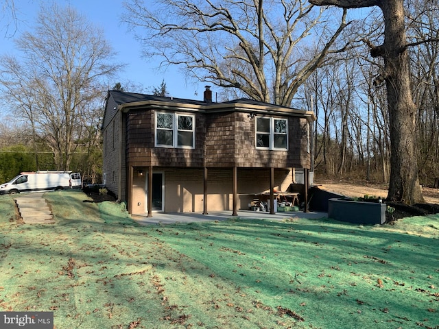 back of house with a patio, a lawn, and a chimney