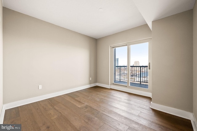 spare room featuring dark wood-style floors and baseboards