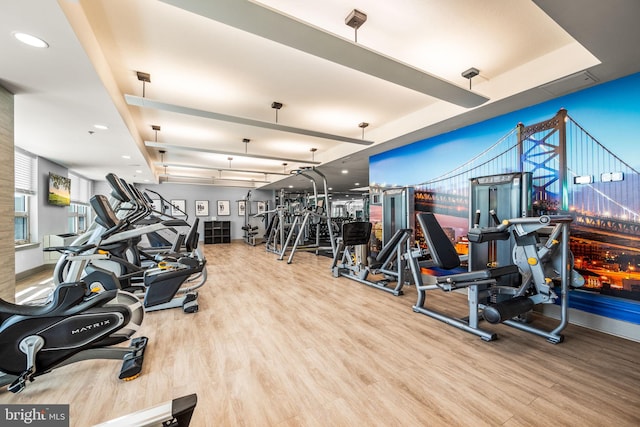 workout area featuring a raised ceiling, wood finished floors, and recessed lighting