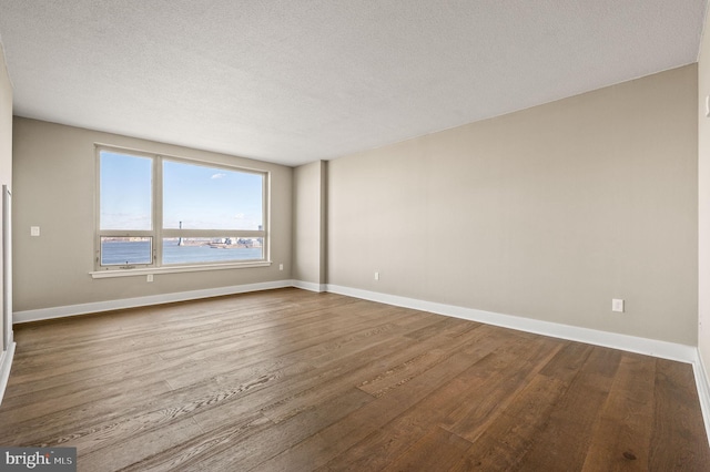 spare room with a textured ceiling, baseboards, and wood finished floors