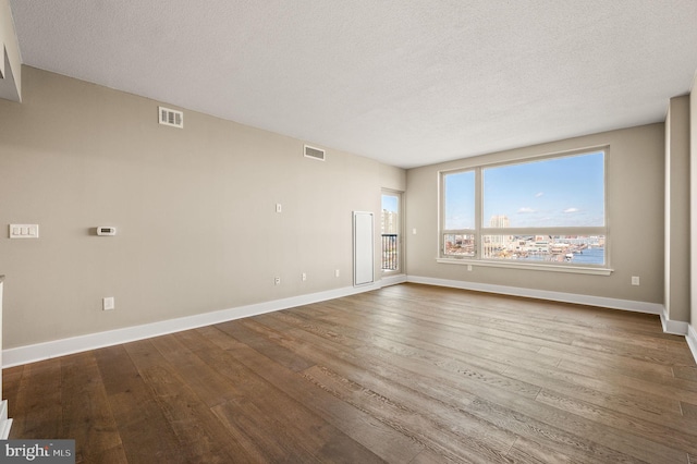 empty room featuring visible vents, baseboards, and wood finished floors