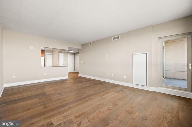 unfurnished living room featuring visible vents, baseboards, and wood finished floors