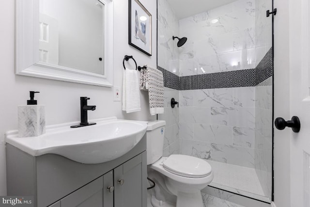 full bathroom featuring toilet, marble finish floor, tiled shower, and vanity