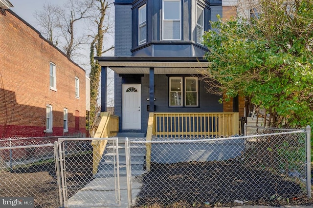 view of front of property with a porch, a fenced front yard, a gate, and brick siding