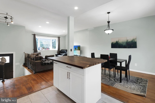 kitchen with wooden counters, recessed lighting, hanging light fixtures, white cabinetry, and open floor plan