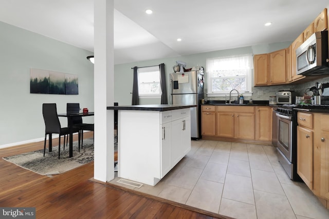 kitchen with decorative backsplash, dark countertops, appliances with stainless steel finishes, and a healthy amount of sunlight