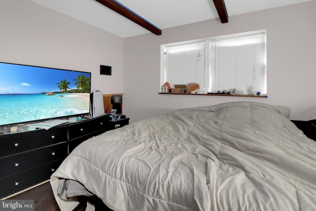 bedroom with beamed ceiling and wood finished floors