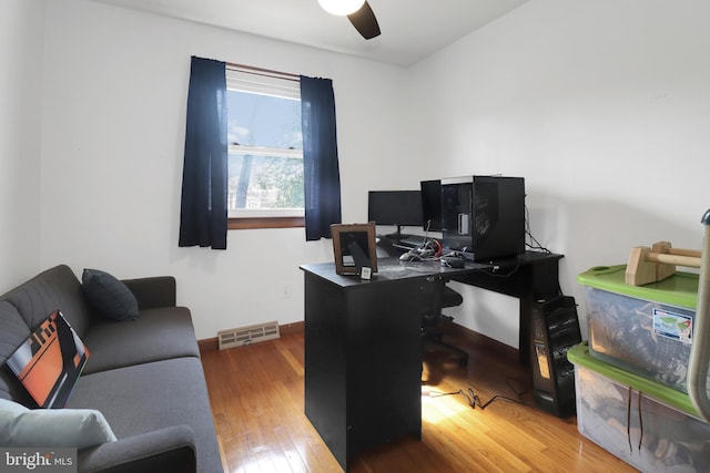 home office featuring hardwood / wood-style floors, a ceiling fan, and visible vents