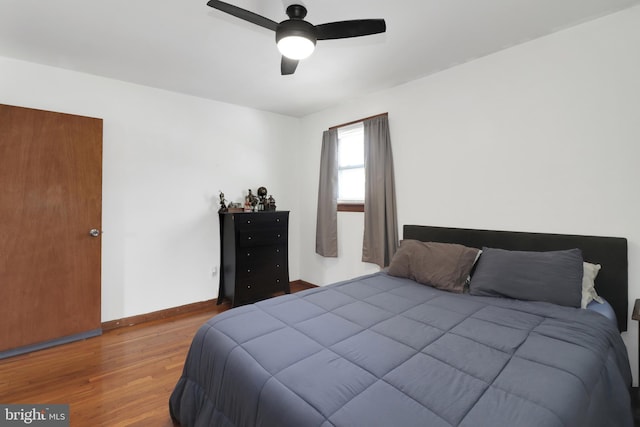 bedroom featuring ceiling fan, baseboards, and wood finished floors