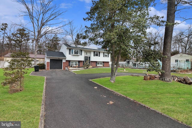 split foyer home with brick siding, a garage, driveway, and a front yard