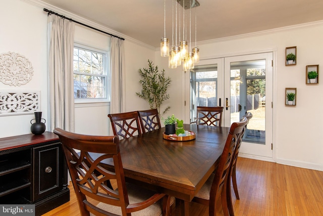 dining space with light wood-style flooring, baseboards, ornamental molding, and french doors